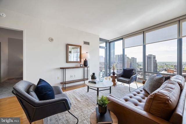 living room featuring a healthy amount of sunlight, floor to ceiling windows, a city view, and visible vents