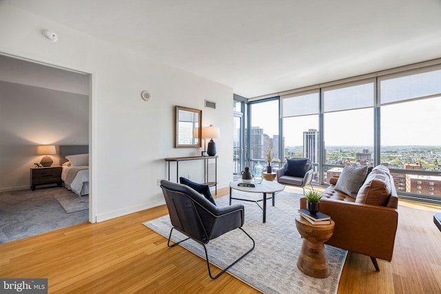 living room with visible vents, a city view, baseboards, and wood finished floors