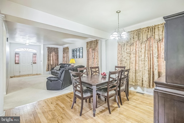 dining room with light wood-type flooring, a chandelier, visible vents, and ornate columns