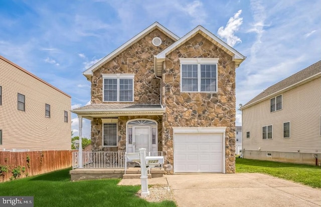 traditional-style house with a front lawn, stone siding, a porch, and an attached garage