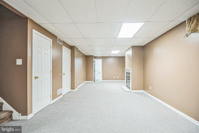 finished basement with visible vents, stairway, carpet flooring, a paneled ceiling, and baseboards
