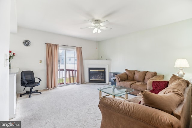 living room featuring a ceiling fan, baseboards, a glass covered fireplace, and carpet