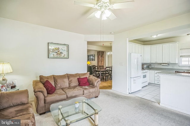 living area featuring light colored carpet, a toaster, baseboards, and a ceiling fan