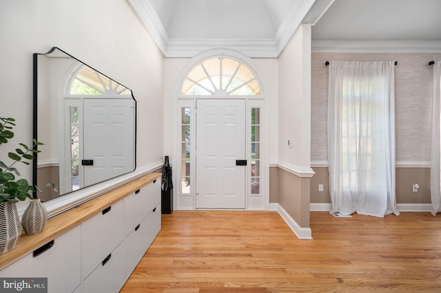 foyer featuring light wood-style floors, ornamental molding, baseboards, and lofted ceiling