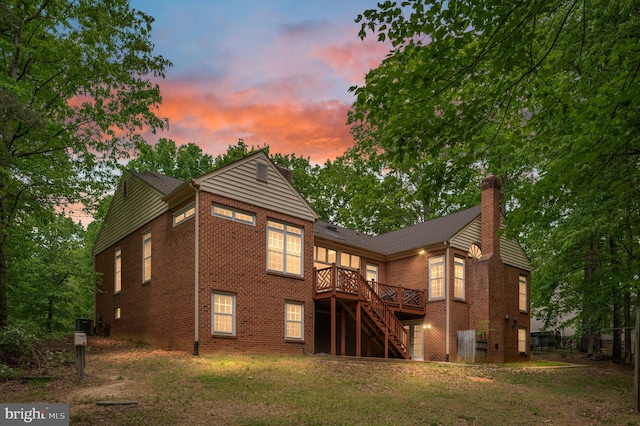 rear view of property featuring a chimney, a wooden deck, brick siding, fence, and stairs