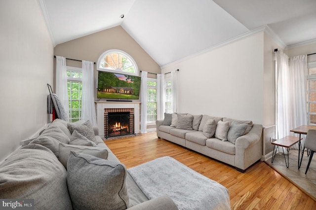living area with a brick fireplace, crown molding, wood finished floors, and lofted ceiling