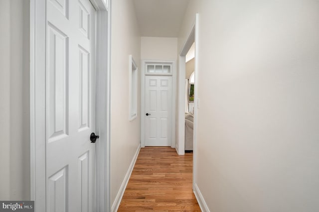 corridor with baseboards and light wood finished floors