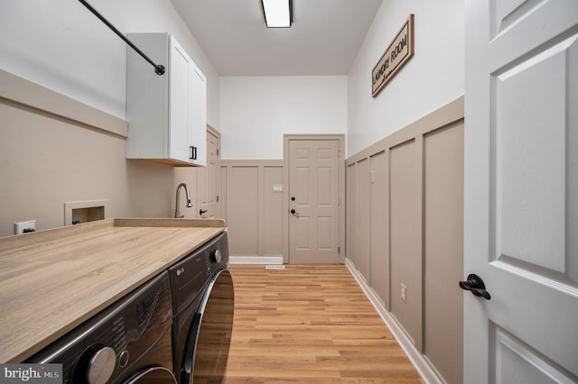 washroom featuring separate washer and dryer, cabinet space, and light wood-type flooring