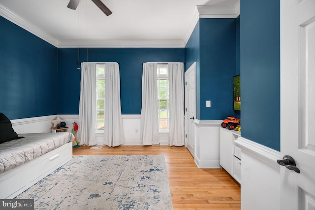 interior space featuring wainscoting, a ceiling fan, ornamental molding, and light wood finished floors