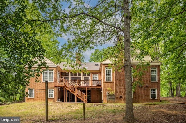 back of property with a wooden deck, stairs, a sunroom, and brick siding
