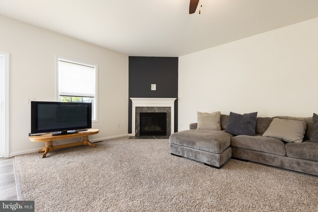 living area with a ceiling fan, baseboards, and a high end fireplace