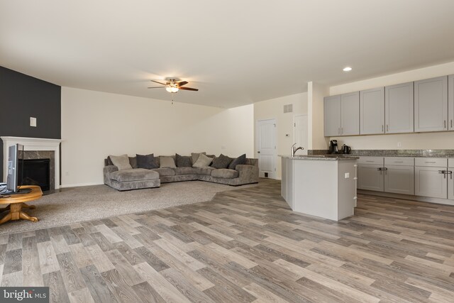 living area featuring visible vents, a ceiling fan, light wood finished floors, and a premium fireplace