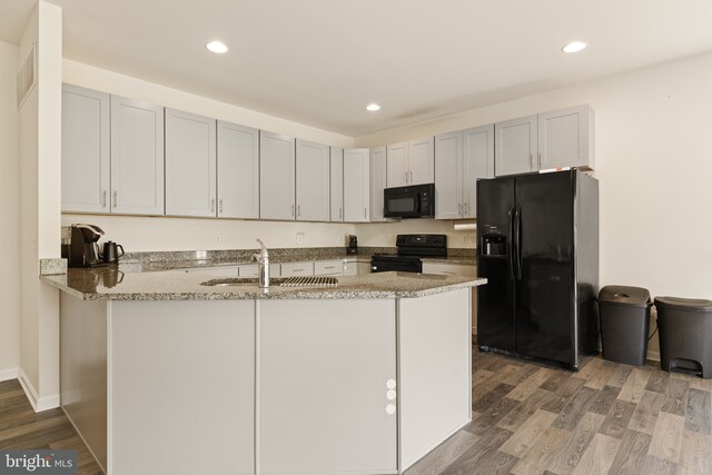 kitchen featuring light stone counters, a sink, light wood finished floors, visible vents, and black appliances