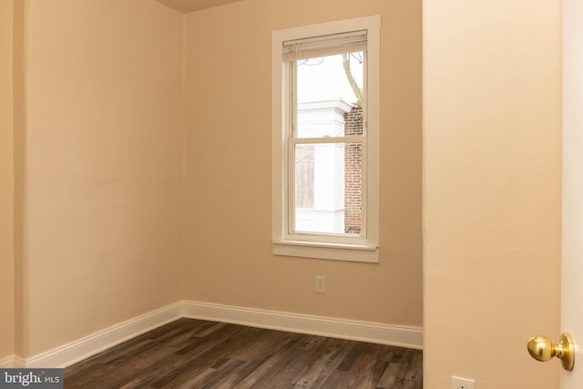 empty room with baseboards and dark wood-type flooring