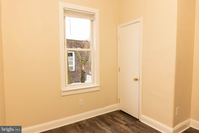 spare room with baseboards and dark wood-style floors