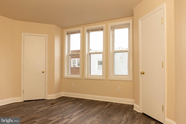 empty room with dark wood finished floors and baseboards