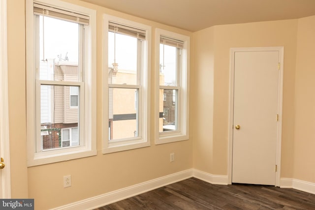 spare room featuring baseboards and dark wood finished floors