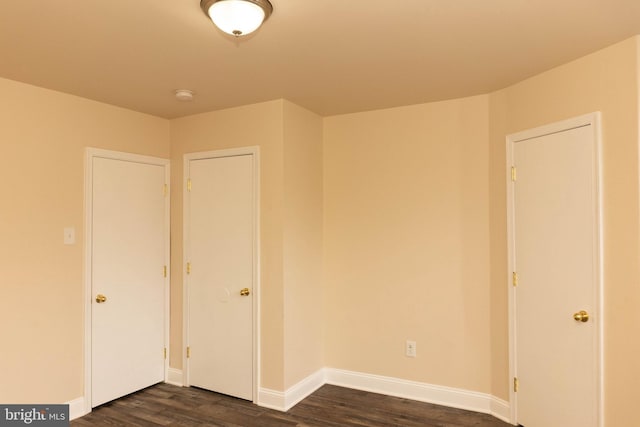 unfurnished room featuring dark wood-type flooring, baseboards, and a smoke detector
