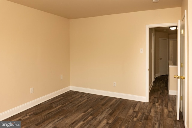 spare room with dark wood finished floors, baseboards, and a smoke detector