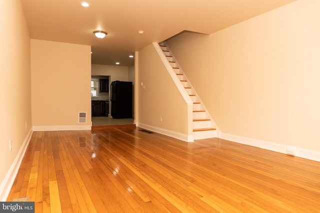 unfurnished living room with hardwood / wood-style flooring, stairway, baseboards, and recessed lighting