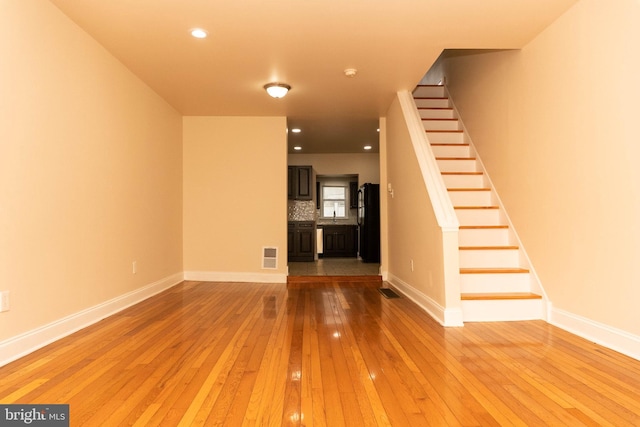 unfurnished living room with hardwood / wood-style floors, stairs, baseboards, and recessed lighting