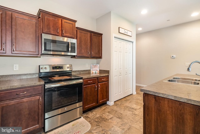 kitchen featuring stone finish floor, stainless steel appliances, recessed lighting, and a sink
