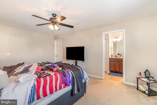 bedroom featuring a ceiling fan, baseboards, light colored carpet, and ensuite bath