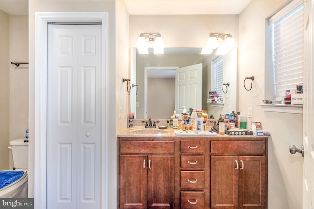 bathroom with vanity, toilet, and a closet