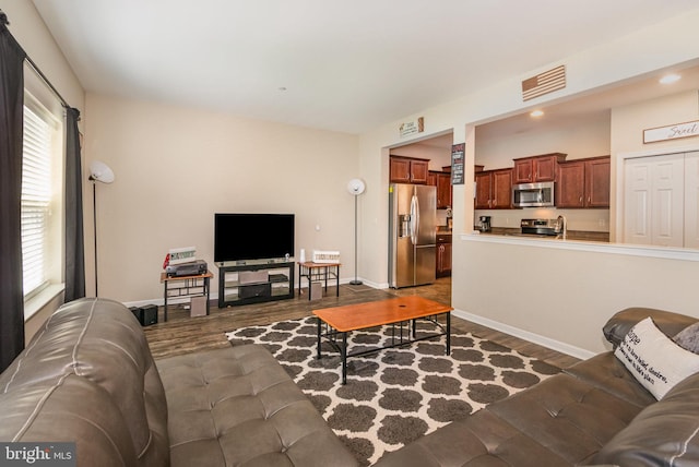 living room with visible vents, baseboards, and dark wood-style floors