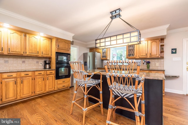 4690 Derby Ln, Doylestown, PA 18902 - kitchen featuring black appliances, ornamental molding, light wood finished floors, a breakfast bar, and tasteful backsplash