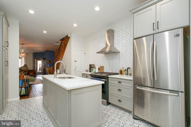 kitchen featuring decorative backsplash, recessed lighting, wall chimney exhaust hood, a sink, and stainless steel appliances