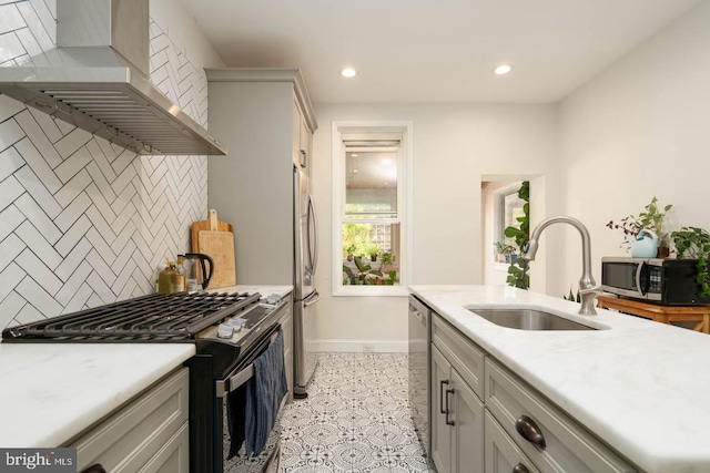 kitchen with backsplash, a sink, baseboards, stainless steel appliances, and wall chimney exhaust hood