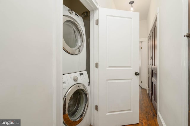 clothes washing area with laundry area, dark wood-style flooring, and stacked washer / dryer