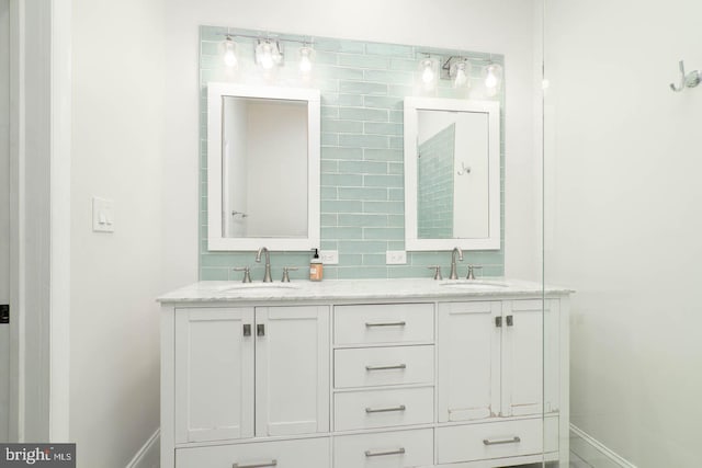 bathroom with double vanity, a sink, baseboards, and decorative backsplash