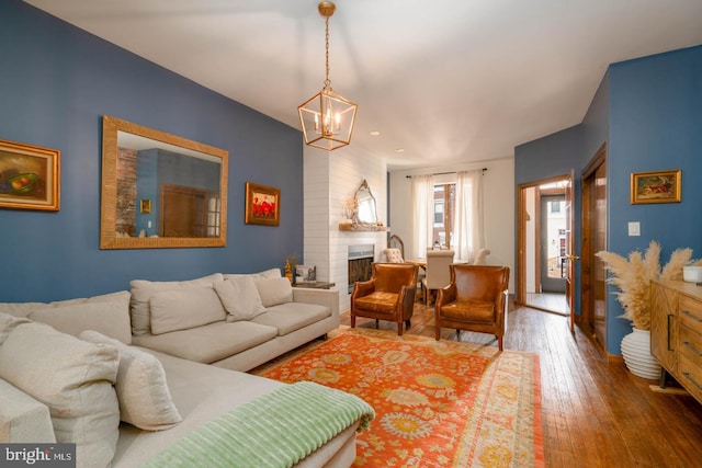 living area featuring a fireplace, wood-type flooring, and a notable chandelier