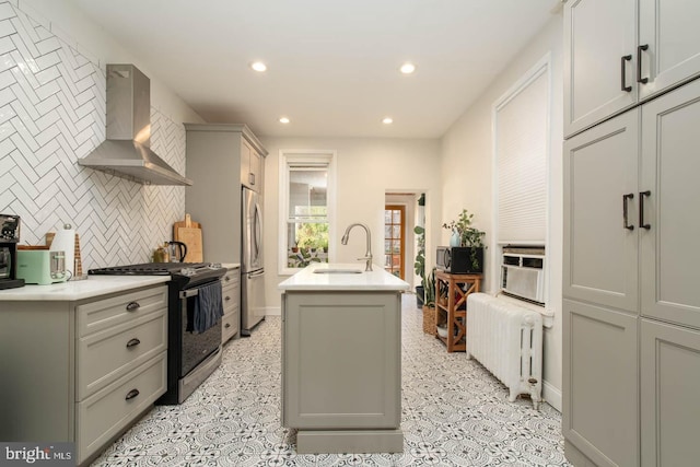 kitchen with wall chimney range hood, gas stove, a sink, radiator heating unit, and freestanding refrigerator