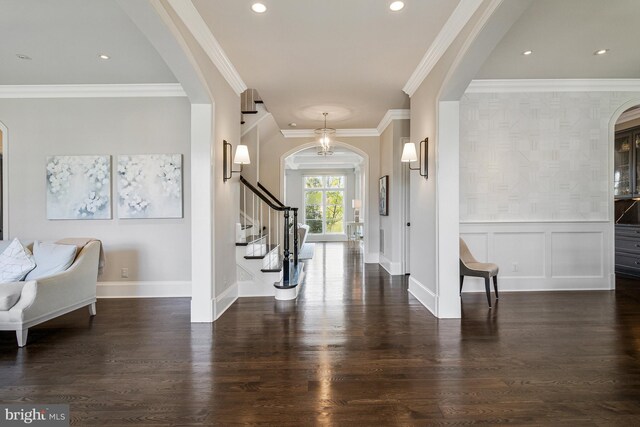 foyer with crown molding, arched walkways, wood finished floors, baseboards, and stairs