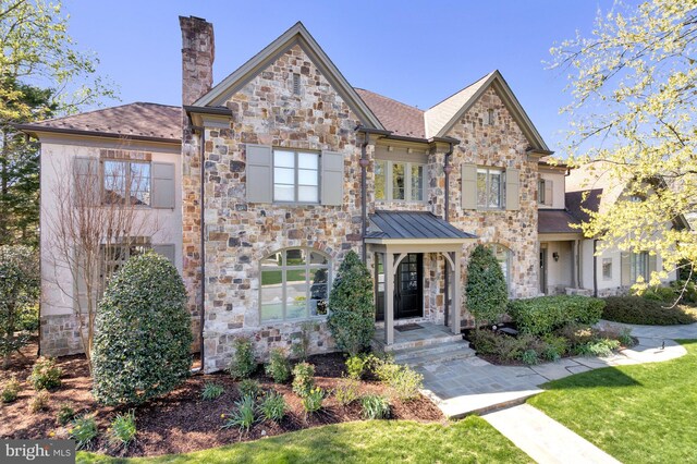 view of front facade with a chimney and stone siding