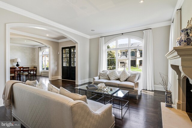 living area featuring arched walkways, baseboards, and dark wood-style floors