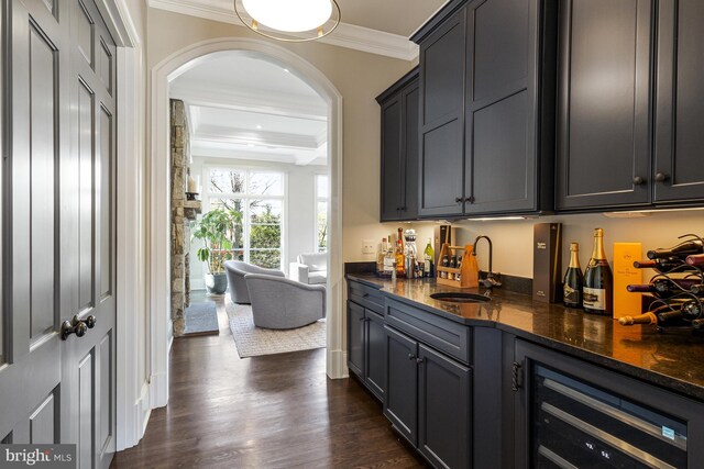bar with crown molding, wine cooler, indoor wet bar, arched walkways, and a sink