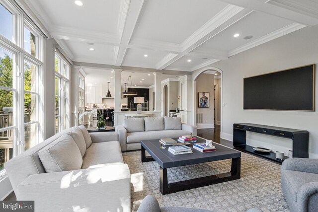 living area with ornamental molding, beamed ceiling, recessed lighting, arched walkways, and coffered ceiling