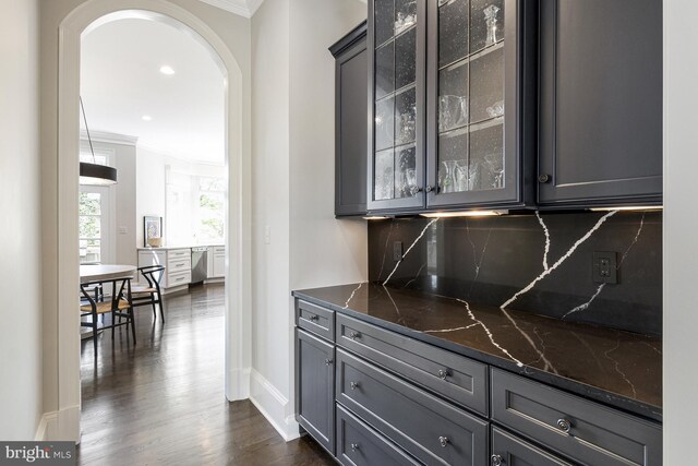 bar with crown molding, tasteful backsplash, arched walkways, dark wood-type flooring, and stainless steel dishwasher