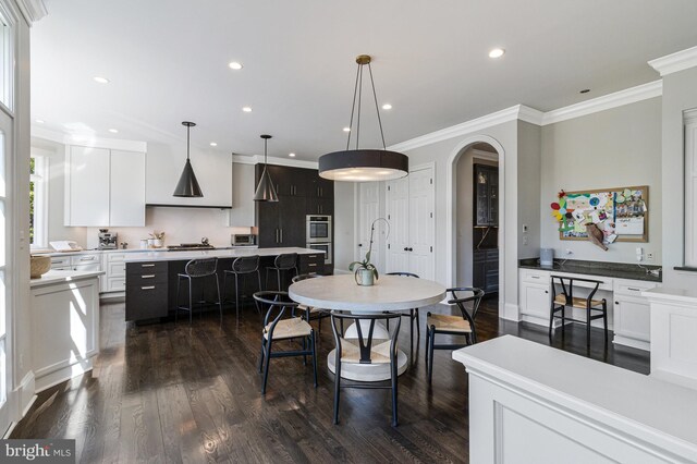 kitchen featuring dark wood-style flooring, ornamental molding, wall chimney exhaust hood, and a center island