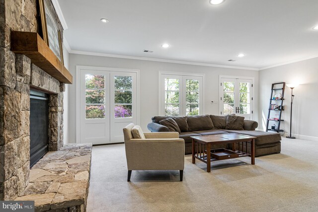 living area featuring a stone fireplace, recessed lighting, crown molding, and light carpet