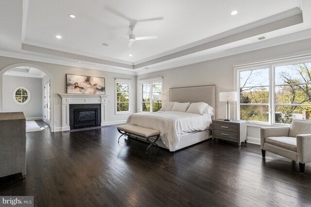 bedroom with arched walkways, a tray ceiling, dark wood-style floors, and visible vents