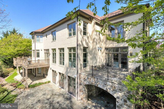 rear view of property featuring a wooden deck, stucco siding, and a patio area