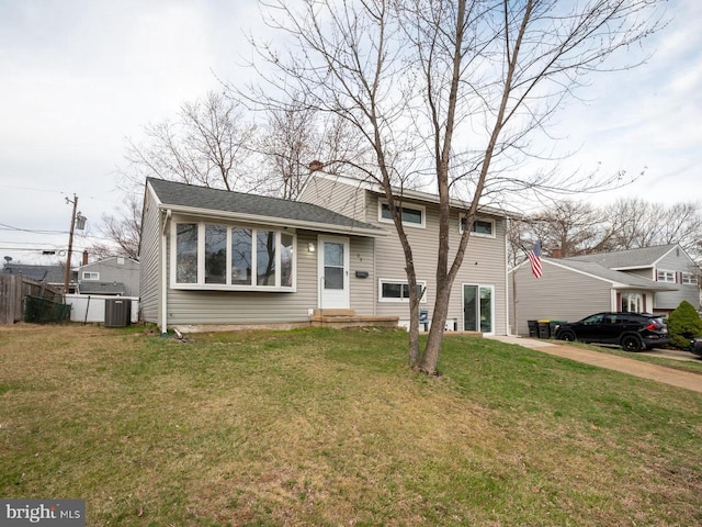 view of front of house with roof with shingles, fence, cooling unit, a front lawn, and entry steps