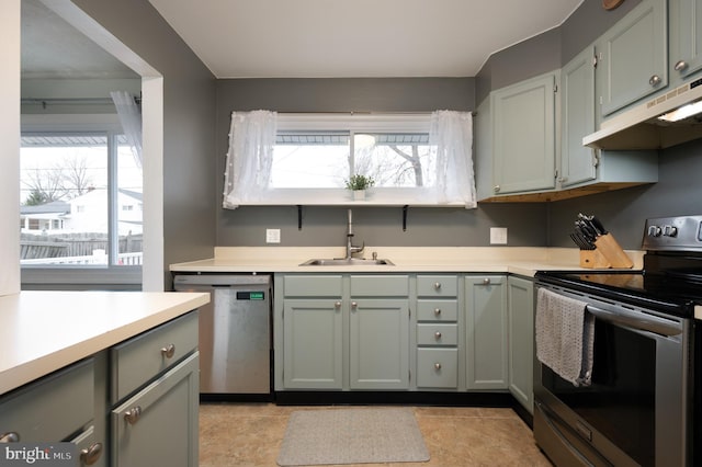kitchen with a sink, appliances with stainless steel finishes, under cabinet range hood, and light countertops