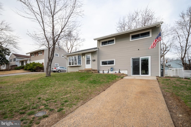 back of property featuring a lawn, fence, and driveway