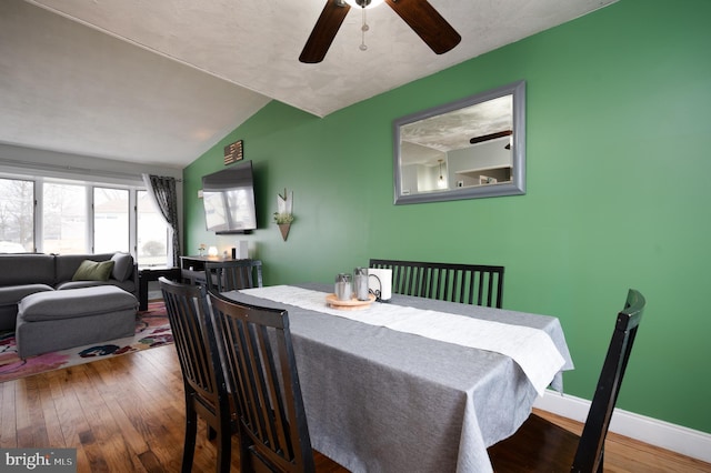 dining area featuring baseboards, ceiling fan, vaulted ceiling, and hardwood / wood-style flooring